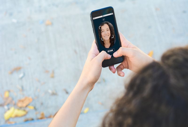 Woman unlocking smartphone with facial recognition technology