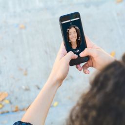 Woman unlocking smartphone with facial recognition technology. Biometric verification and face recognition concept. All screen graphics are made up by us