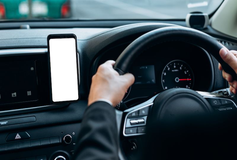 Blank empty screen smartphone on holder in car use for Navigation or GPS. Car interior view