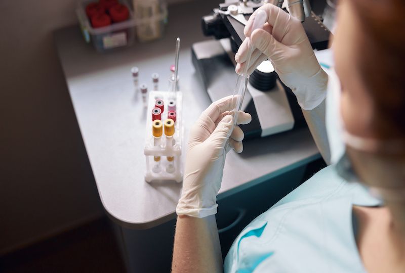 Female lab tech takes sample from test tube to research material at workplace with modern equipment