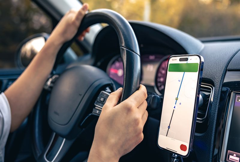 Woman using navigation app on smartphone while driving a car.